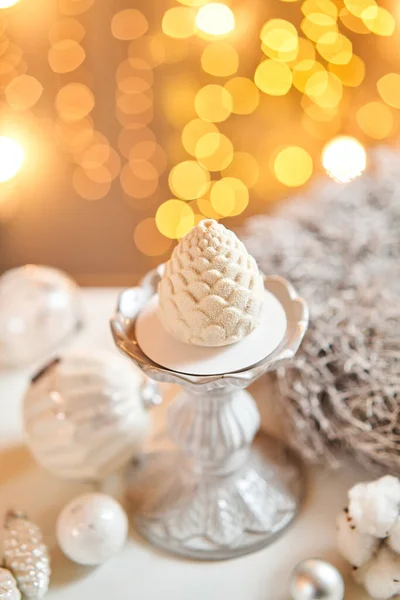 Επιδόρπιο σε μορφή κουκουναριού των Χριστουγέννων. Μίνι μους γλυκό καλυμμένο με βελούδο. Λάμπες Γκάρλαντ στο βάθος. Σύγχρονη ευρωπαϊκή τούρτα. Γαλλική κουζίνα. Χριστουγεννιάτικο θέμα. Αντιγραφή χώρου — Φωτογραφία Αρχείου