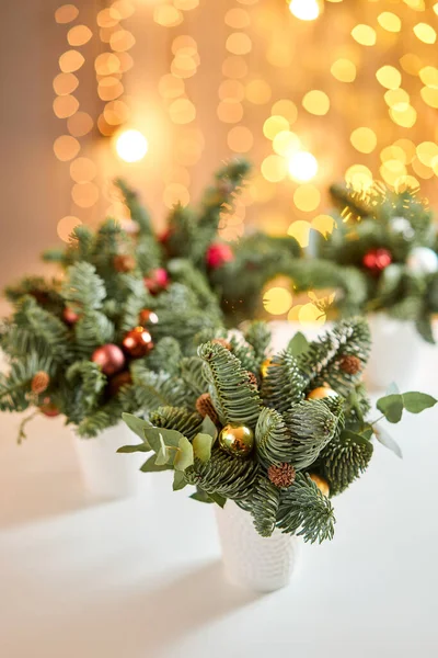 Χριστουγεννιάτικη σύνθεση με Νορβηγικό πεύκο Nobilis και διακοσμημένο με χριστουγεννιάτικη διακόσμηση σε ένα κύπελλο κεραμικής. Ο Γκάρλαντ Μπόκεχ στο βάθος. Χριστουγεννιάτικη αγάπη. Σκούρο ξύλινο τραπέζι πασπαλισμένο με χιόνι — Φωτογραφία Αρχείου