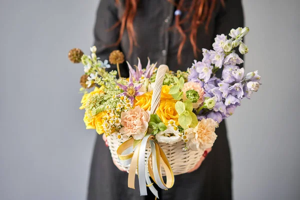 위커 바구니 에서 꽃꽂이를 한다. 여인의 손에는 아름다운 혼합 꽃들의 꽃다발이 있다. 꽃다발도 예쁘고. 작은 꽃 가게와 화 꽃 배달 — 스톡 사진