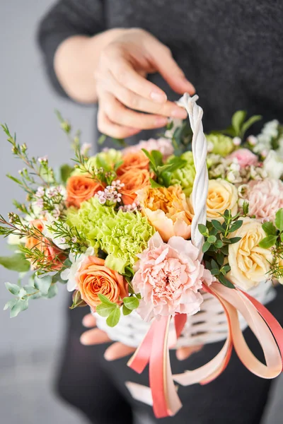 Kleine bloemenwinkel en bloemen levering. Bloemenarrangement in rieten mandje. Mooi boeket van gemengde bloemen in de hand van de vrouw. Mooi vers boeket. — Stockfoto