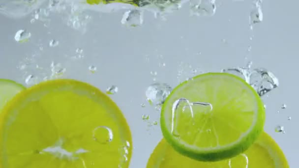 Limes and oranges dropped in water — Stock Video