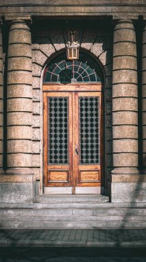 Eski ahşap kapılı metal ızgaralı tarihi binaların taş sütunları arasında, yakın çekim güneş ışığı manzaralı