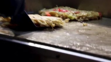 Okonomiyaki Japon sokak yemekhanesinde ızgara yapıyor.