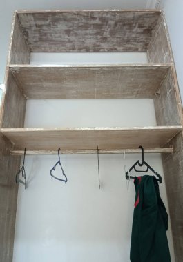 Duvarında elbise askısı olan boş ahşap raflar