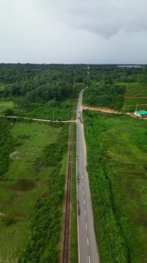 Sylhet Bangladeş 'teki yemyeşil çay bahçelerinin ve kırsal yolun hava aracı manzarası tepeler, orman ve demiryolu manzarasıyla çevrili.