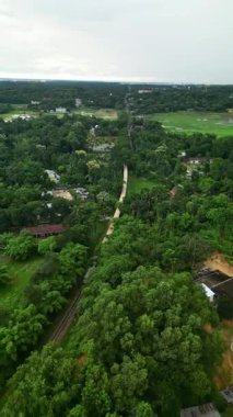 Sylhet Bangladeş 'teki yemyeşil çay bahçelerinin ve kırsal yolun hava aracı manzarası tepeler, orman ve demiryolu manzarasıyla çevrili.