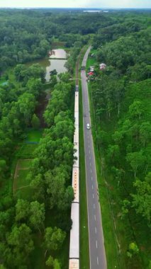 Sylhet Bangladeş 'teki yemyeşil çay bahçelerinin ve kırsal yolun hava aracı manzarası tepeler, orman ve demiryolu manzarasıyla çevrili.