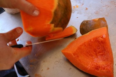 Erkek ellerinin önlük giydiği yakın plan bir sokak yemekhanesinde çorba için kabak soyarken ve keserken.