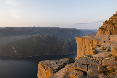 Preikestolen - Norveç'te Rock şaşırtıcı. Bulutların üstünde bir uçurumun üzerinde duran kız. Müezzin kayası, Ryfylke, en ünlü turistik Lysefjord üzerinde kuleleri