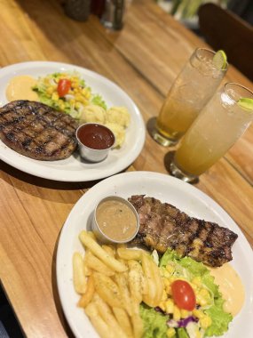 Lezzetli bir biftek, kızarmış patates ve ferahlatıcı bir içecek, yemek blogları ve restoran menüleri için mükemmel. Taze malzemeler ve canlı renkler.