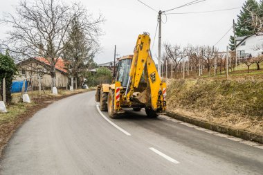 Novi Sad, Sırbistan - Şubat 05. 2020: Çalışan makine JCB JS 220 NLC 'yi izledi. Sırbistan 'ın Novi Sad kenti yakınlarındaki Fruska Gora Dağı' nın zirvesine çıkan ana kırsal yolda çalışan bir makine.. 