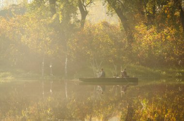 Novi Sad, Sırbistan - 22 Ekim 2015: Novi Sad kenti yakınlarında küçük bir doğal göl. Gölün kıyısına demirlemiş ahşap balıkçı tekneleri, ilk sabah güneşiyle aydınlanıyor..