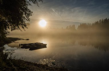 Novi Sad, Sırbistan - 22 Ekim 2015: Novi Sad kenti yakınlarında küçük bir doğal göl. Gölün kıyısına demirlemiş ahşap balıkçı tekneleri, ilk sabah güneşiyle aydınlanıyor..