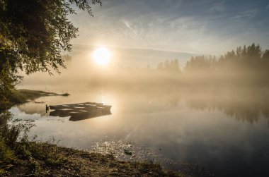 Novi Sad, Sırbistan - 22 Ekim 2015: Novi Sad kenti yakınlarında küçük bir doğal göl. Gölün kıyısına demirlemiş ahşap balıkçı tekneleri, ilk sabah güneşiyle aydınlanıyor..
