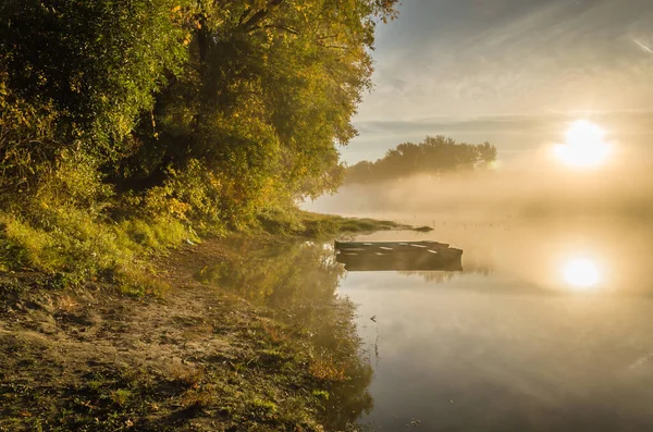 Novi Sad, Sırbistan - 22 Ekim 2015: Novi Sad kenti yakınlarında küçük bir doğal göl. Gölün kıyısına demirlemiş ahşap balıkçı tekneleri, ilk sabah güneşiyle aydınlanıyor..