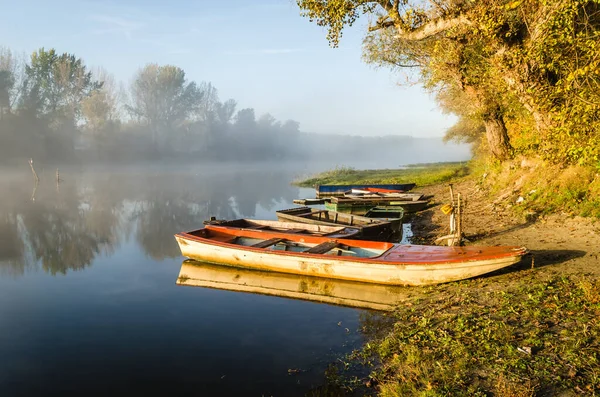 Novi Sad, Serbia - October 22, 2015: A small natural lake near the city of Novi Sad. Wooden fishing boats moored on the shores of the lake, illuminated by the first morning sun.