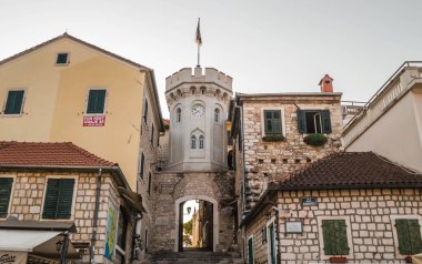 Herceg Novi, Karadağ - 23 Ağustos 2021: Eski evlerle çevrili küçük saat kulesiyle eski kasaba kapısı