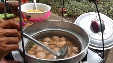 Köfte satıcısının müşterinin siparişini hazırlayan yakın plan fotoğrafı. Çorbadan yükselen buhar lezzetli lezzeti artırır. Endonezya sokak yemekleri, erişteli biftek köftesi.