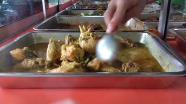Endonezya 'daki tipik bir Cava Nasi Tegal tezgahında çeşitli yemekler cam bir vitrinde servis edilir. Müşterilere servis yapan bir satıcının sipariş verdiği mezeleri yakın çekim görüntüsü..