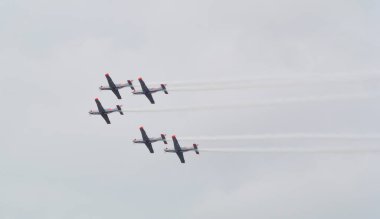 Uçaklar akrobatik manevralar yaparak renkli dumanlar bırakarak yumuşak bulutlarla akşam gökyüzüne doğru bir çember oluşturuyorlar.
