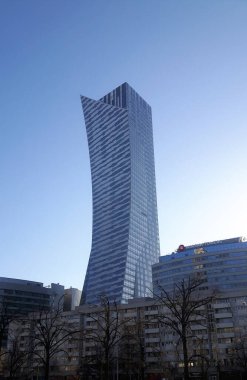 Varşova binalarının üzerinde kıvrımlı bir biçime sahip uzun camdan bir gökdelen şehrin modernliğini ve dinamik gelişimini vurguluyor..