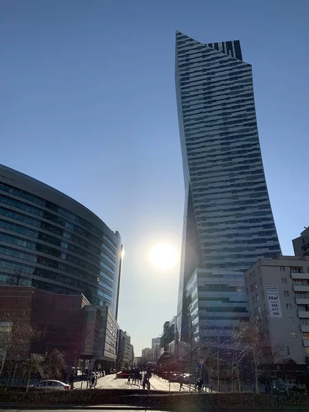 Güneş, Varşova modern gökdelenleri arasında yükseliyor, cam cephelere parlak yansımalar yapıyor ve canlı şehir merkezinin dinamik atmosferini vurguluyor..