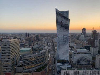 Günbatımında Varşova 'nın merkezinde modern bir gökdelen, ofis binaları, yollar ve yoğun kentsel gelişim ile çevrili..