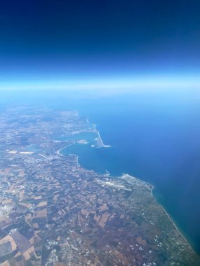 Limanı, tarımsal alanları ve mavi ufku olan bir deniz kıyısının havadan görünüşü. Seyahat, ulaşım, lojistik, ekoloji ve uzay kavramı.