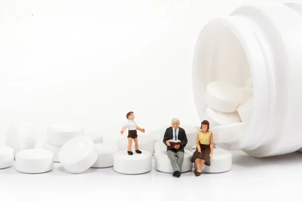 Miniature people - people posing in front of pills — Stock Photo, Image