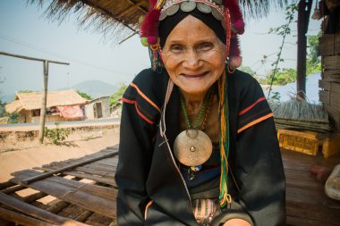 Akha etnik gruptan yaşlı bir kadın duruyor gölgesinde 