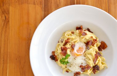 Spagetti Carbonara gevrek domuz pastırması ve yumurta beyaz plaka üzerinde