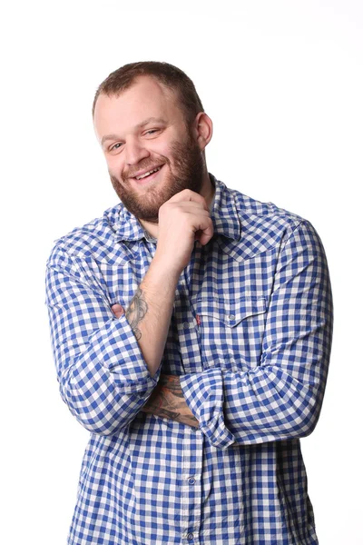 Smiling young man with a beard in plaid shirt looking at camera