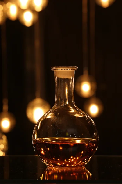 Round bottle with drink against blur bokeh light — Stock Photo, Image