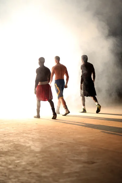 Entrenamiento de boxeo de tres jóvenes en un viejo edificio — Foto de Stock