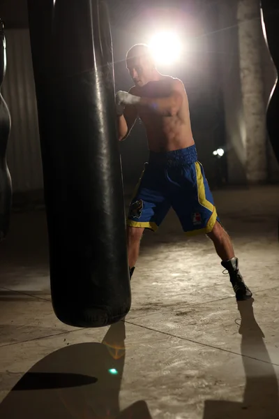 Boxeador masculino afroamericano golpeando saco de boxeo en el gimnasio —  Fotos de Stock
