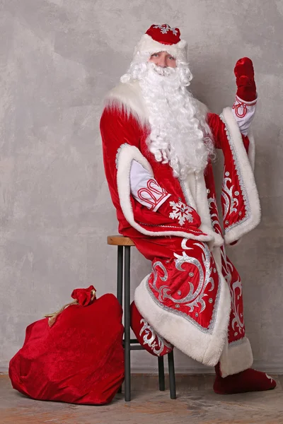 Father Frost in red coat with bag of Christmas gifts — Stock Photo, Image