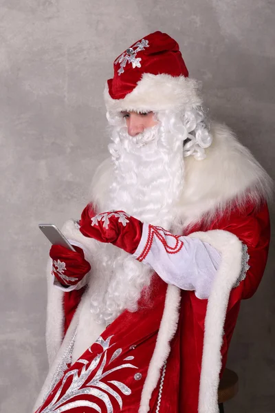 Father Frost looking at mobilephone sitting on chair — Stock Photo, Image