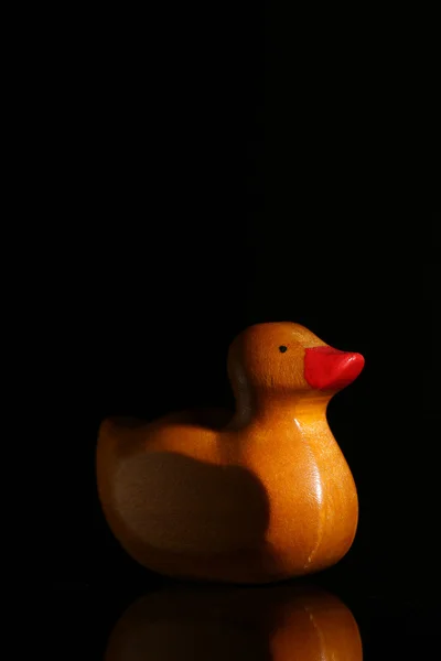 Canard jaune en caoutchouc avec son reflet en verre, fond noir — Photo