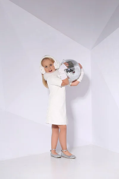 Маленька блондинка з дзеркальною сферою на білому тлі стіни — стокове фото