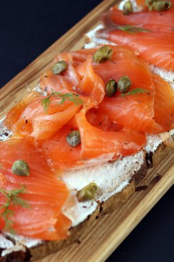 Ahşap tahta üzerinde somon ve krem peynirli ekmek.