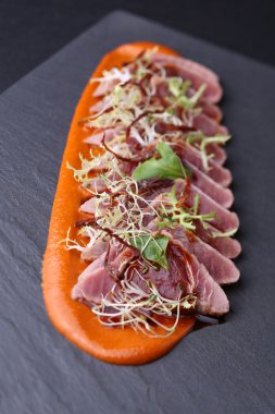 Roka, microgreen ve koyu arka plan üzerinde havuç sosu ile jambon
