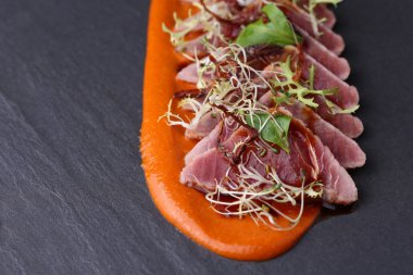 Roka, microgreen ve koyu arka plan üzerinde havuç sosu ile jambon