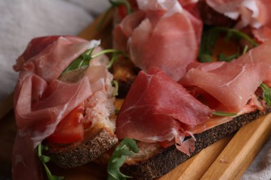 Pastırma, arugula ve domates ile ekmek ahşap panoları üzerinde. Seçici odaklama
