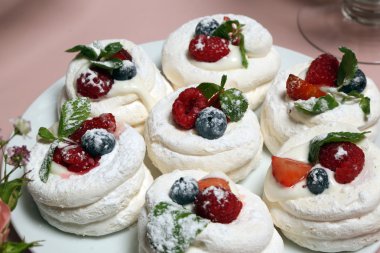 Çilek krema, taze çilek, ahududu, yaban mersini ve nane yaprağı ile beze yuvaları. Closeup