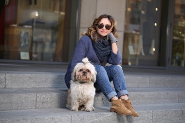 Merdivenlerde oturan shih-tzu köpek ile güneş gözlüğü zarif kadın