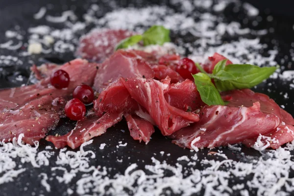 Rundercarpaccio met Parmezaanse kaas en greens op de zwarte achtergrond — Stockfoto