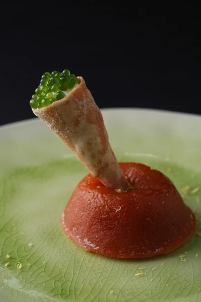 Groene kaviaar in wafer rollen op een fijnmazig rode caviars op witte plaat, zwarte achtergrond — Stockfoto