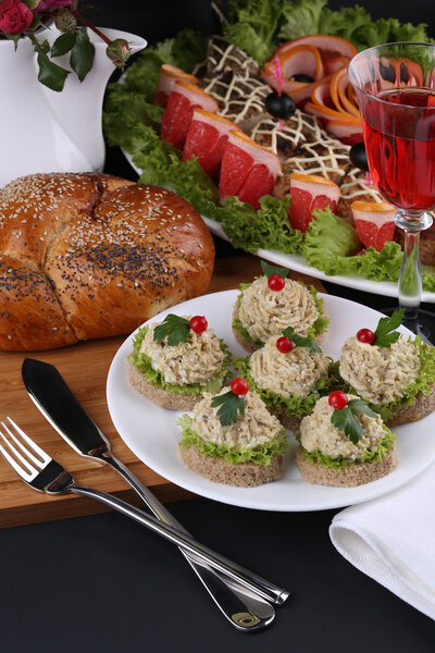 Festive appetizer: sandwich with pate against the backdrop of stuffed fish dishes