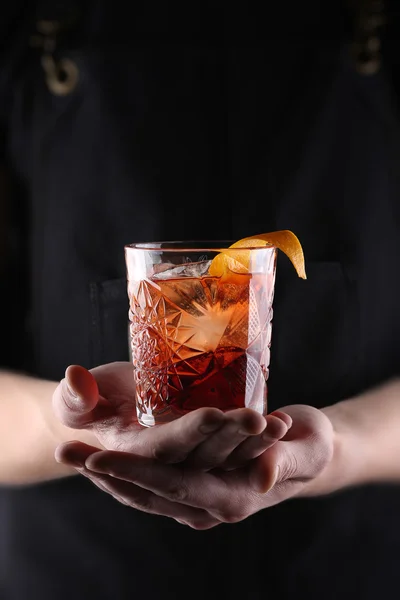 Gammaldags Negroni cocktail i handen på den svarta bakgrunden — Stockfoto
