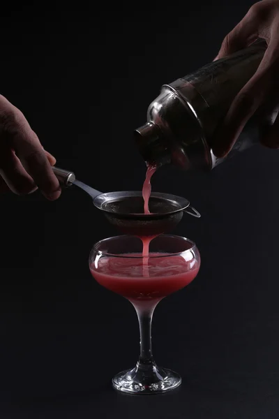 Barman készít koktélt egy magas pohár a sötét háttér. — Stock Fotó